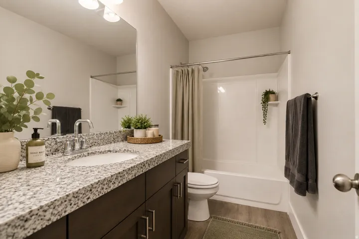 Bathroom featuring a dark wood-finish vanity with a granite-style countertop, undermount sink, chrome faucet, and a large wall-mounted mirror