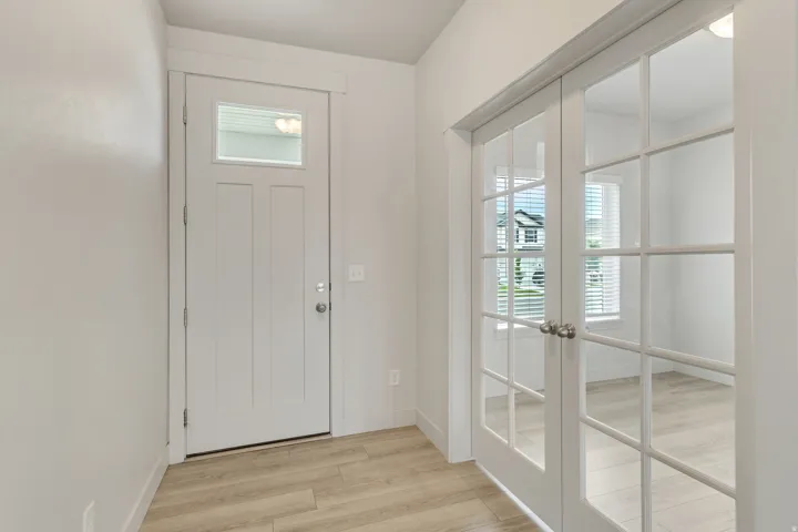 Entryway featuring wood-finish flooring and a white paneled entry door with an upper window