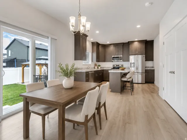 Open-concept kitchen and dining area featuring dark wood-finish cabinetry, stainless steel appliances, and a kitchen island with seating