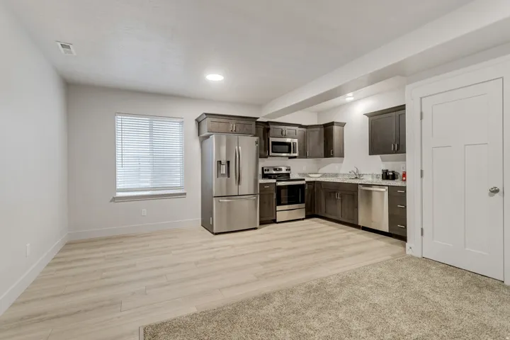 Kitchenette featuring stainless steel appliances, dark wood-finish cabinetry, and light-toned countertops