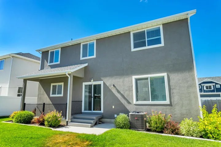 Rear exterior with a covered patio, sliding glass door, and a manicured lawn