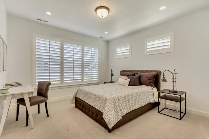 Recessed lighting, ceiling-mounted light fixture, light-colored carpeting, multiple windows with white shutters