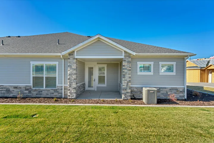 Exterior featuring light grey siding, stone veneer accents, an enclosed porch, and a well-maintained lawn