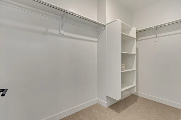 White shelving system, dual hanging rods, and light-toned carpeting