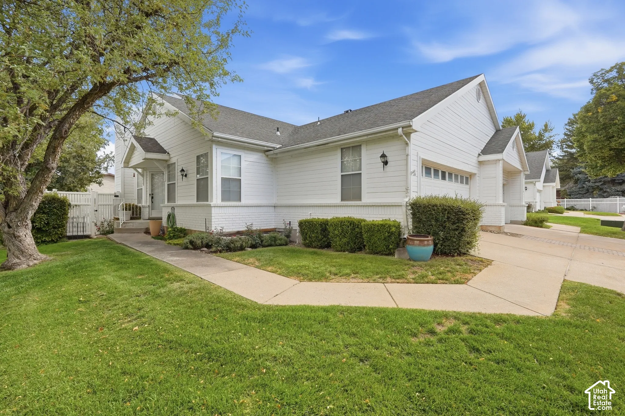 White siding exterior with a pitched roof, front entry porch, attached garage, and a concrete driveway