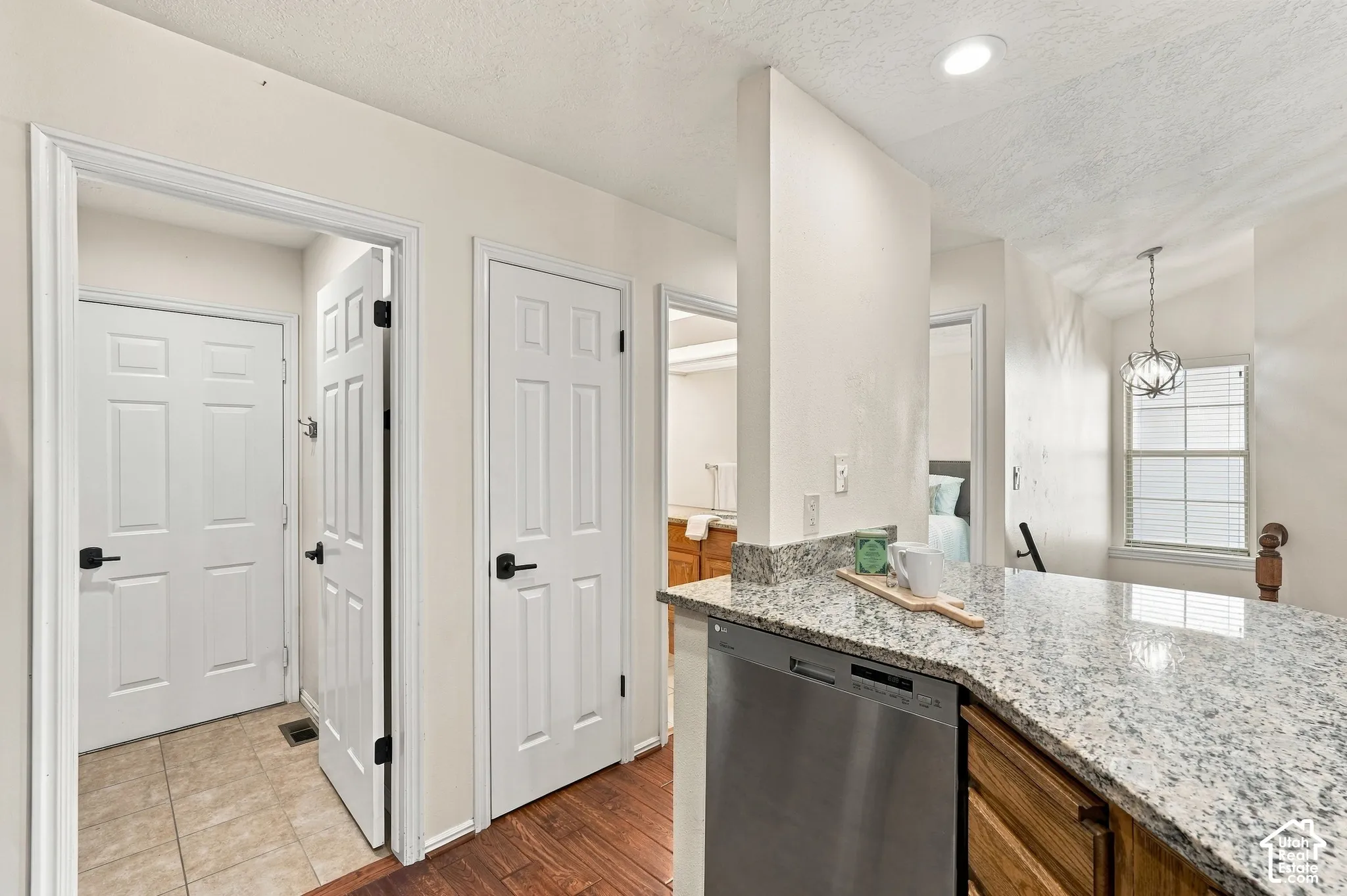 Granite countertop, integrated dishwasher, recessed lighting, wood-finish flooring, and a decorative pendant light fixture