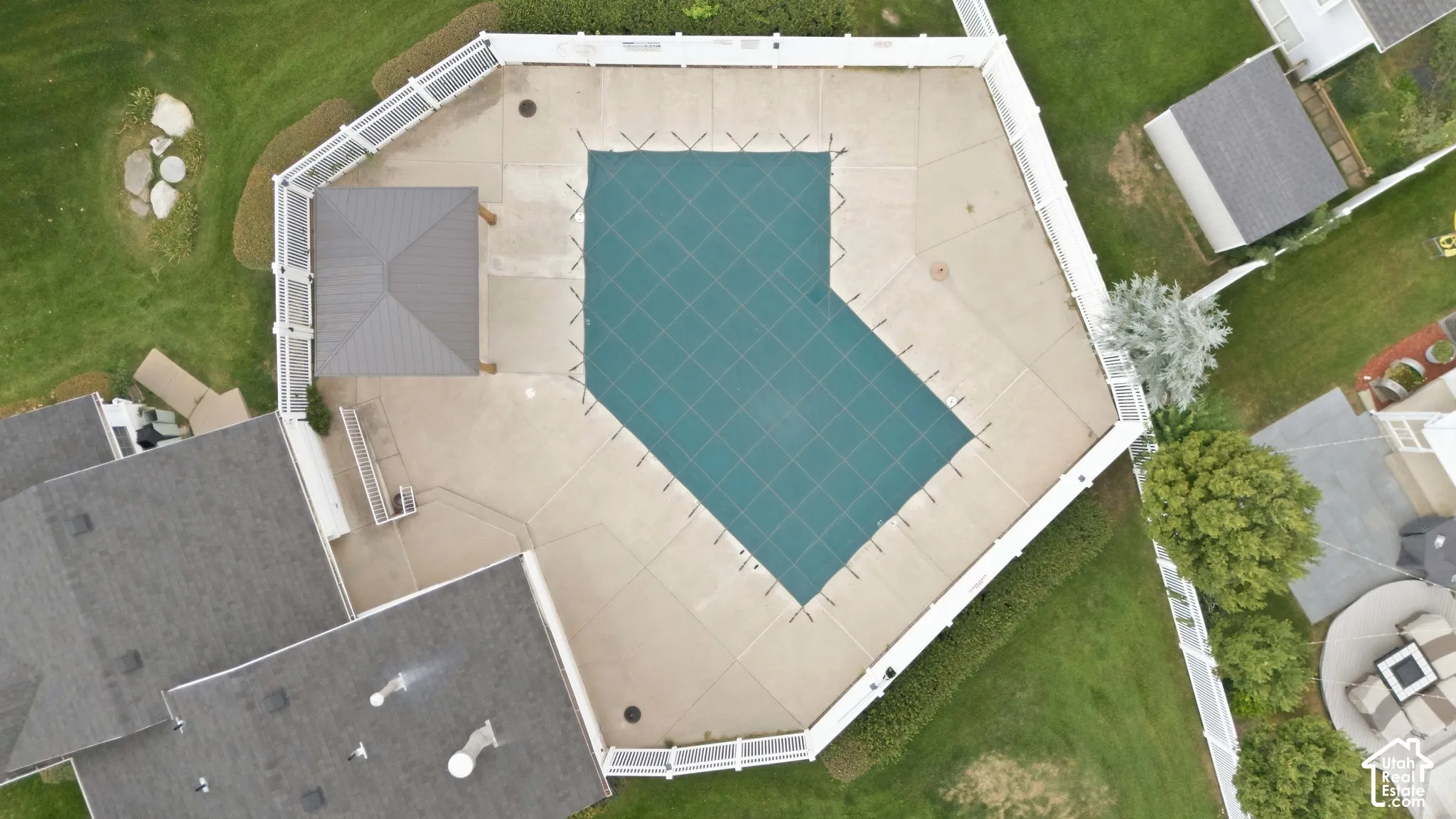 Fenced pool area with a covered pool, surrounding concrete patio, and a shaded pergola
