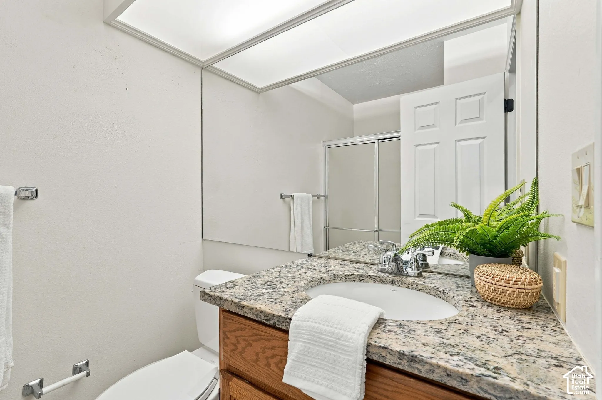 Bathroom vanity with an integrated sink, granite countertop, chrome faucet, and wood-finish cabinetry