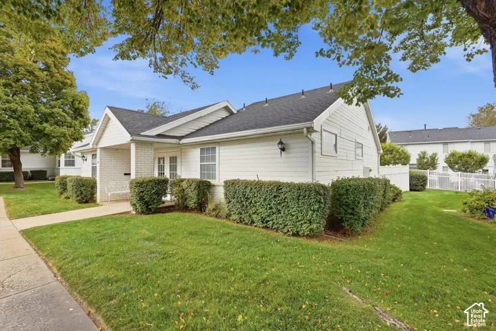 White siding exterior with a brick accent entry, dual front windows, and a paved walkway