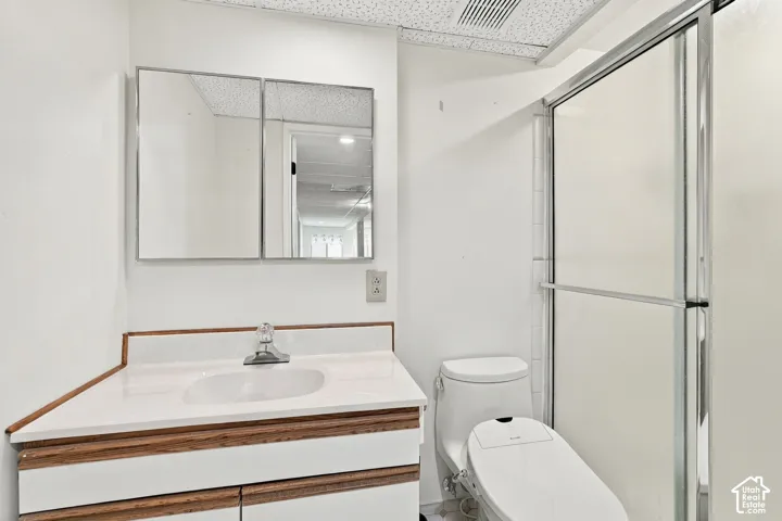 Vanity with white countertop, recessed medicine cabinet, single handle faucet, and a shower with sliding opaque glass doors