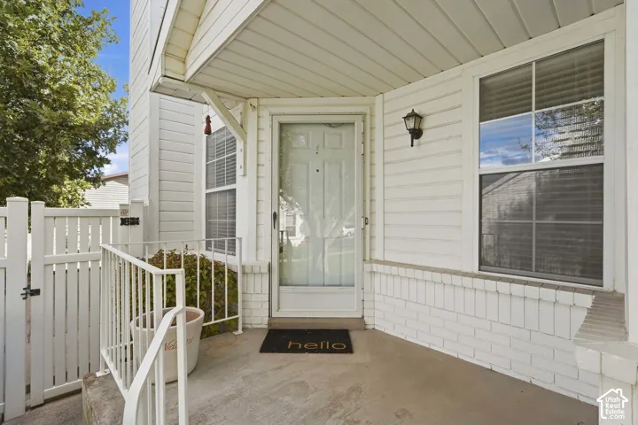Covered entry with white siding, white railing, and decorative wall sconce