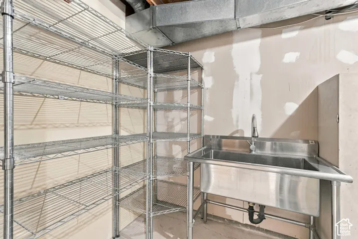Stainless steel utility sink with a tall faucet and ample wire shelving