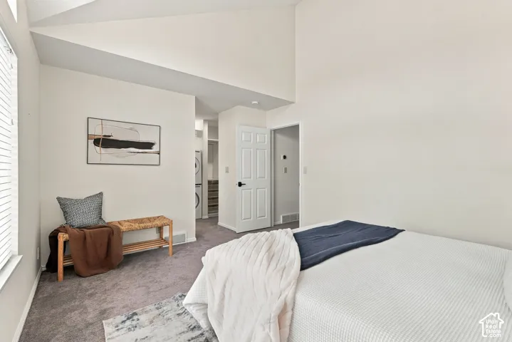 Vaulted ceiling with textured white walls and gray carpet flooring