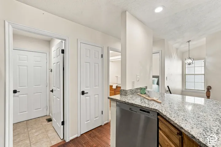 Granite countertop, integrated dishwasher, recessed lighting, wood-finish flooring, and a decorative pendant light fixture
