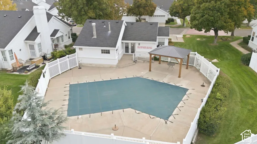 Fenced outdoor pool area with a covered pool and surrounding concrete patio