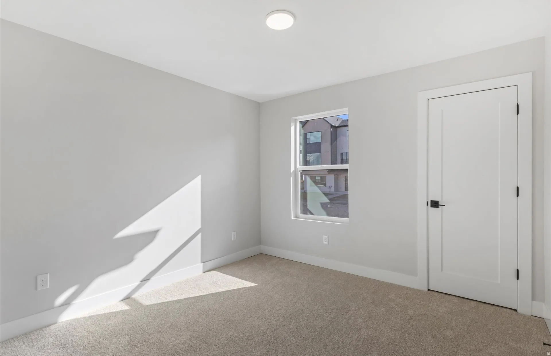 Recessed ceiling light, neutral wall paint, single-hung window, white interior door, and beige carpet flooring