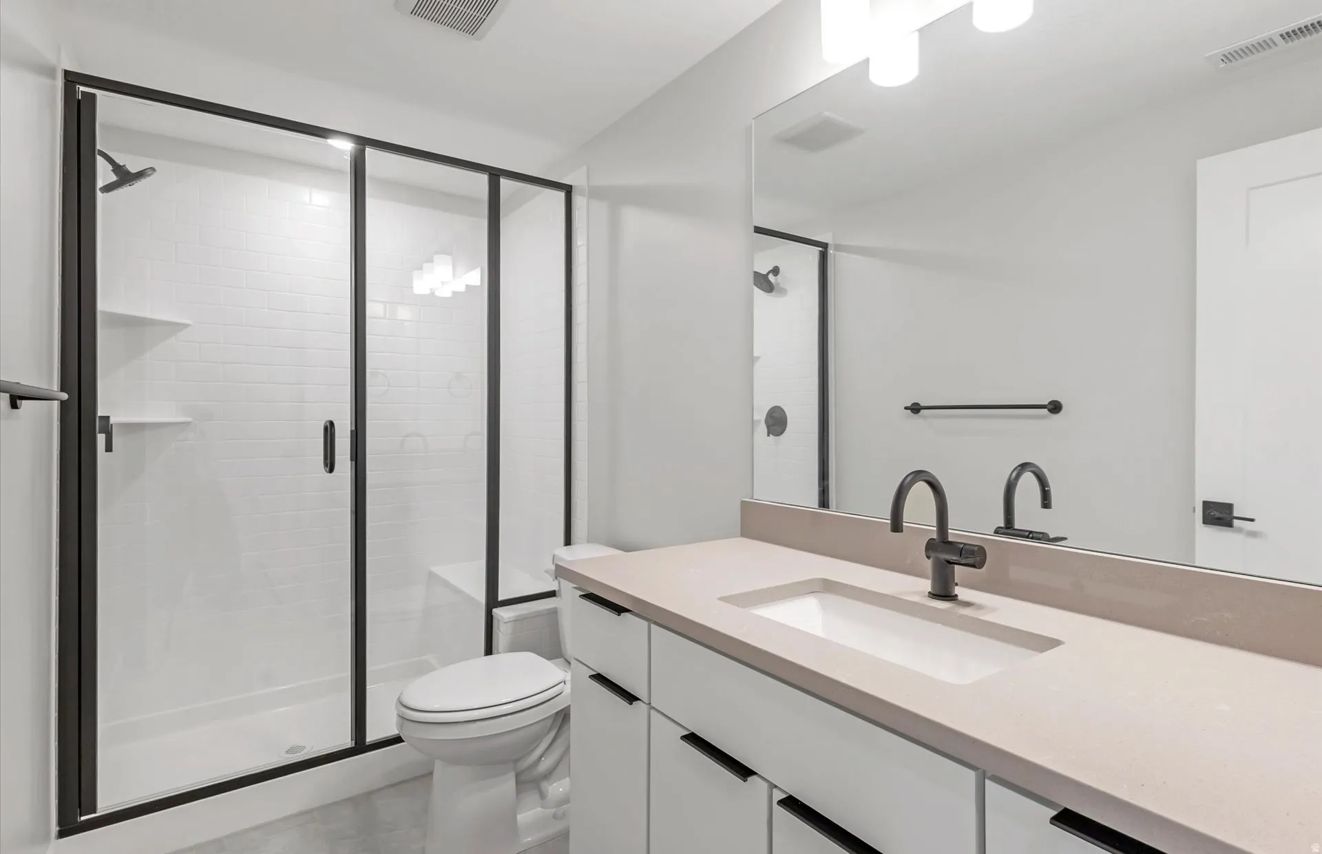 White subway tile shower with a built-in bench and matte black framed glass enclosure