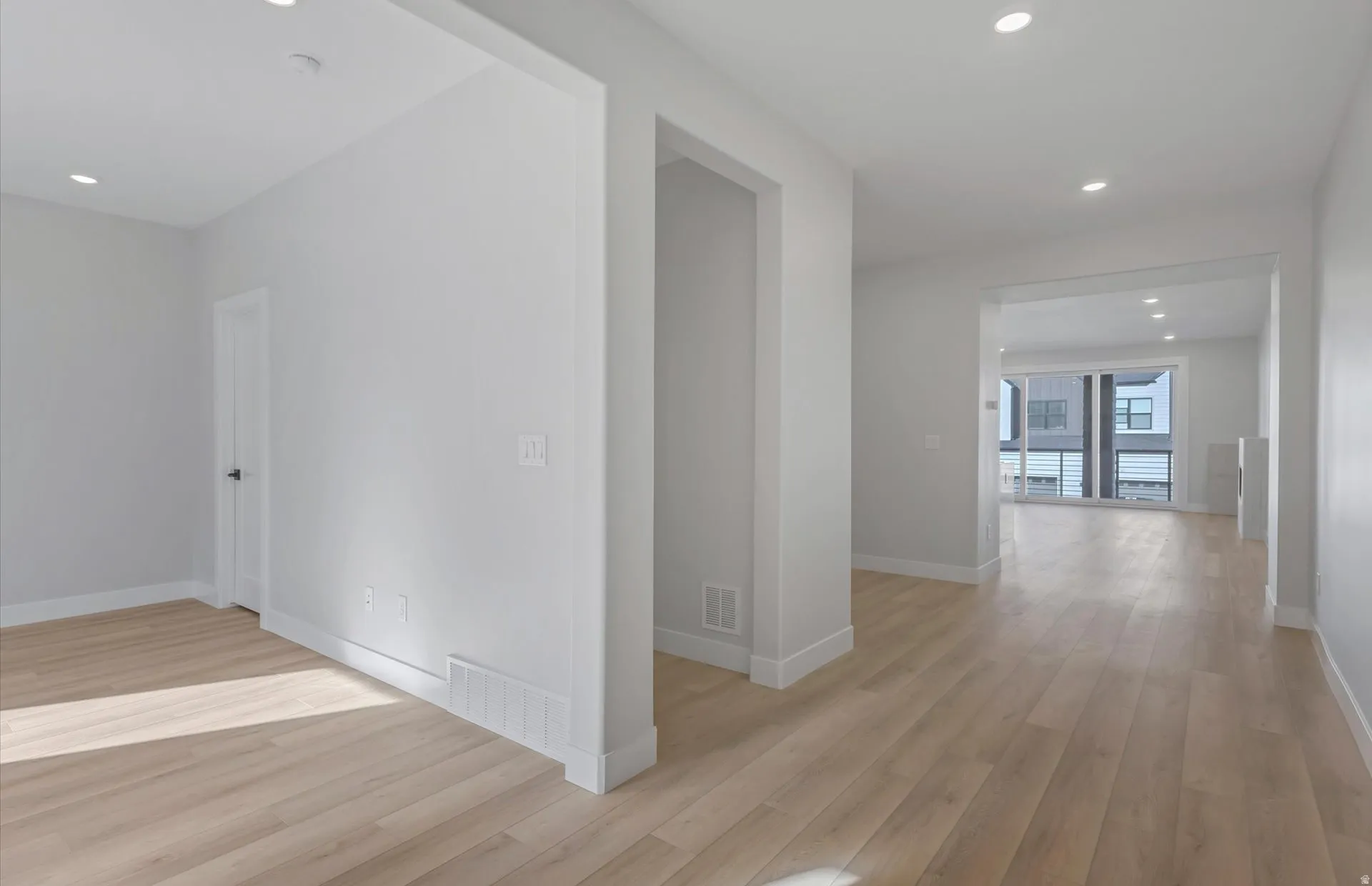 Recessed lighting throughout, wide plank wood-finish flooring, white trim, and a modern neutral color palette