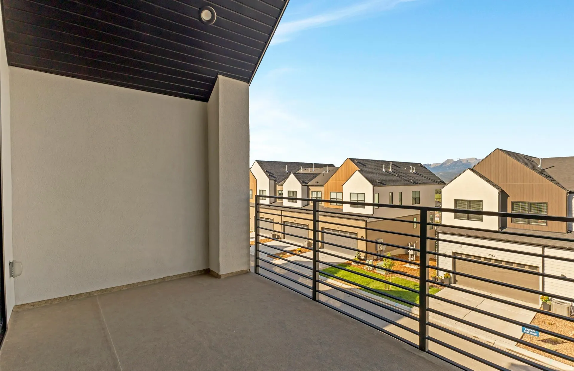 Outdoor balcony with concrete flooring and a black horizontal bar railing