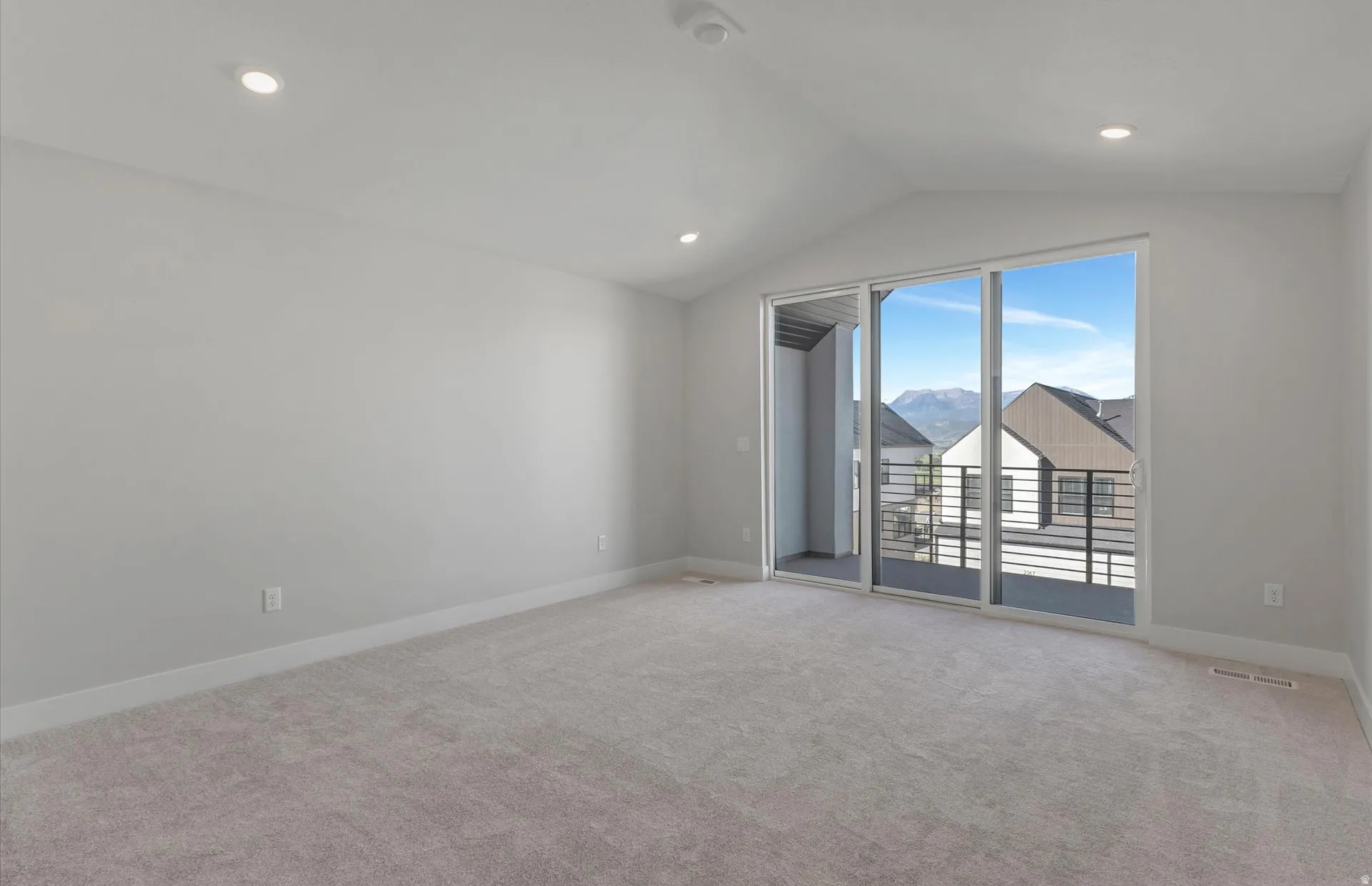 Recessed lighting, sloped ceiling, light-toned carpeting, sliding glass door, and private balcony with metal railing