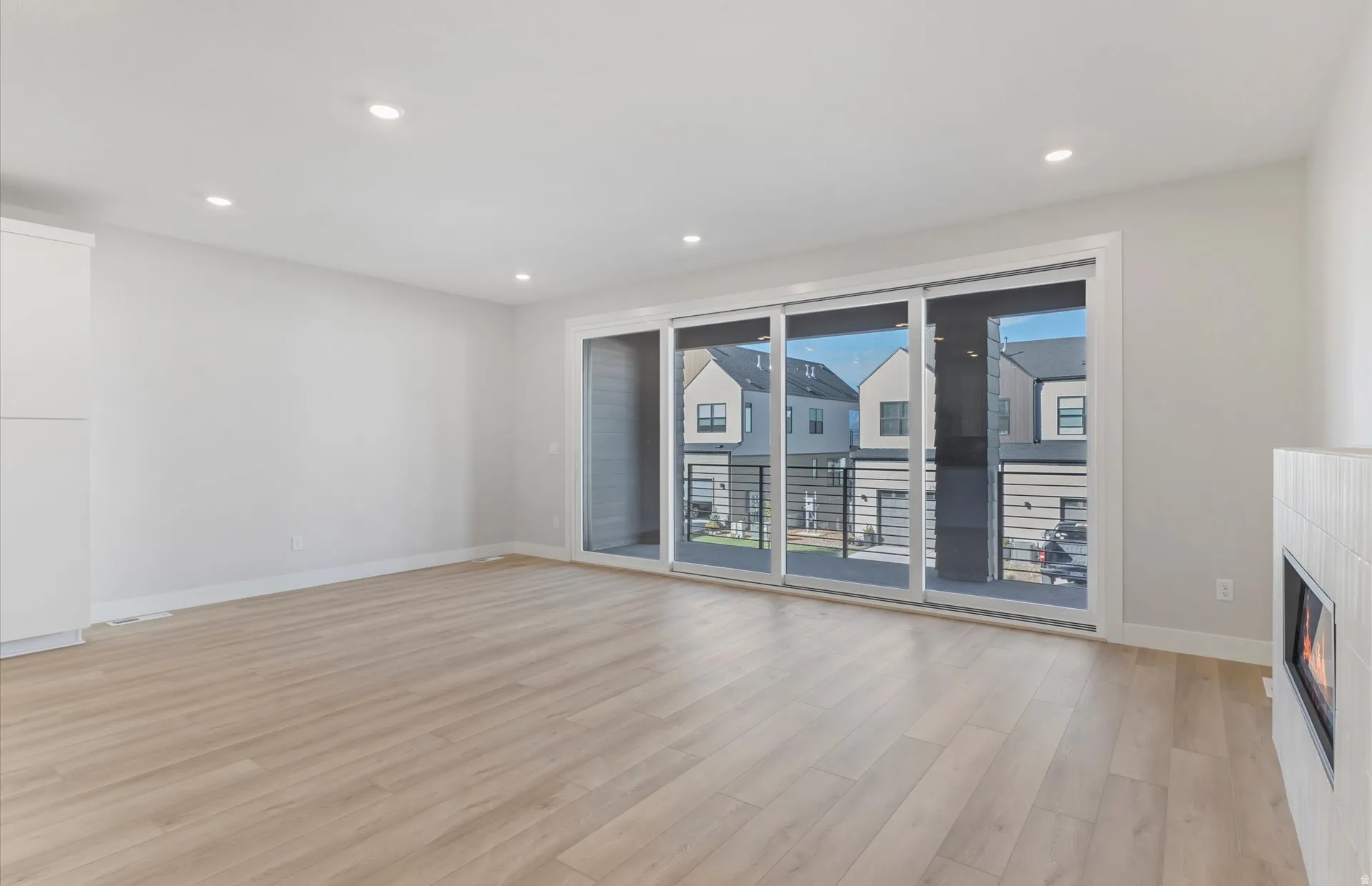 Wood-finish flooring, recessed lighting, and a modern fireplace with tile surround