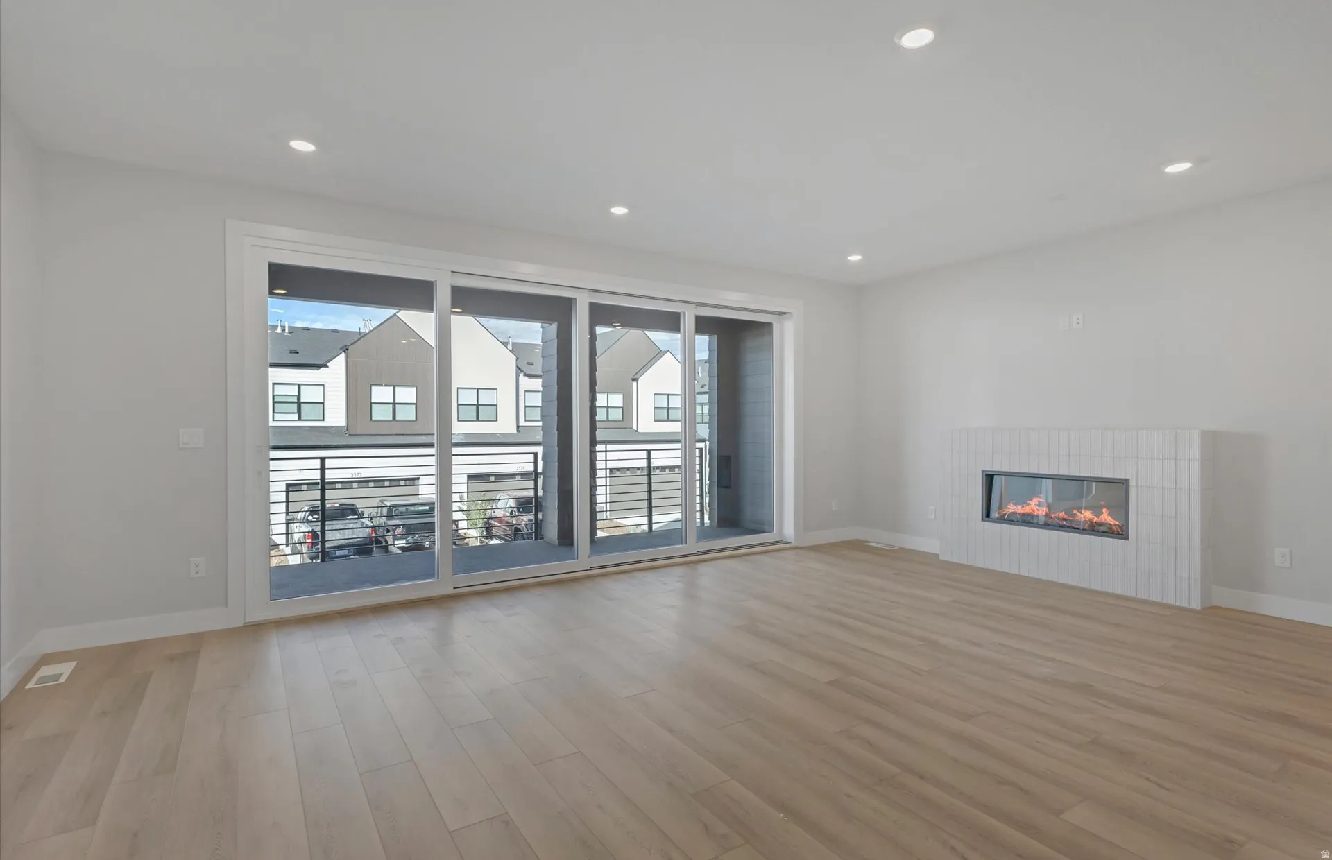 Wood-finish flooring, recessed lighting, and a modern linear fireplace with a tiled surround