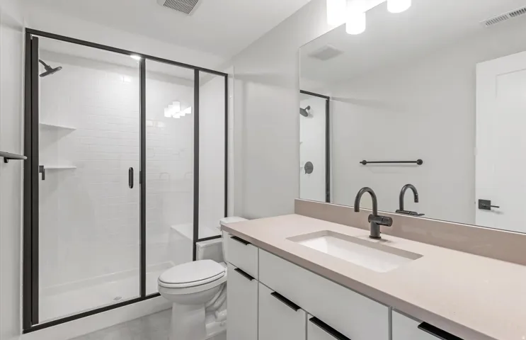 White subway tile shower with a built-in bench and matte black framed glass enclosure
