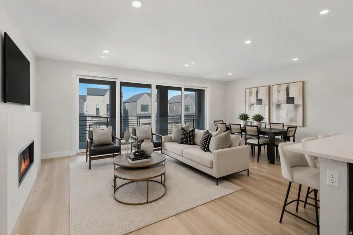 Open-concept living area with multi-panel sliding glass door and fireplace. This image has been digitally staged or enhanced via artificial intelligence. These photos are for illustrative purposes only and do not represent the actual current condition, la