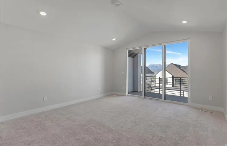 Recessed lighting, sloped ceiling, light-toned carpeting, sliding glass door, and private balcony with metal railing