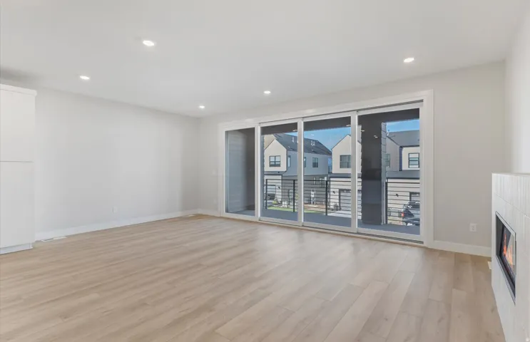 Wood-finish flooring, recessed lighting, and a modern fireplace with tile surround