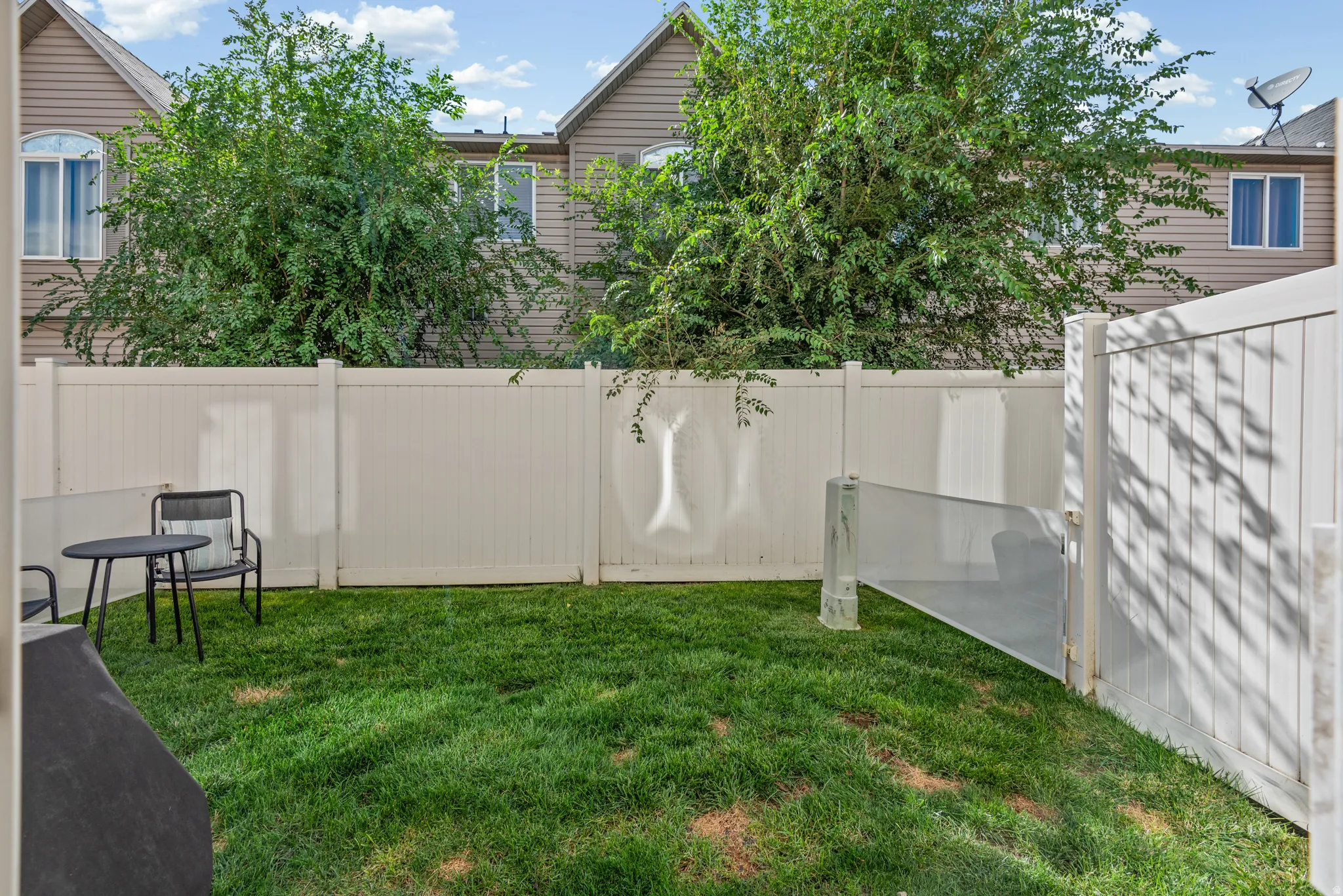 Private backyard with a vinyl fence and a grassy lawn
