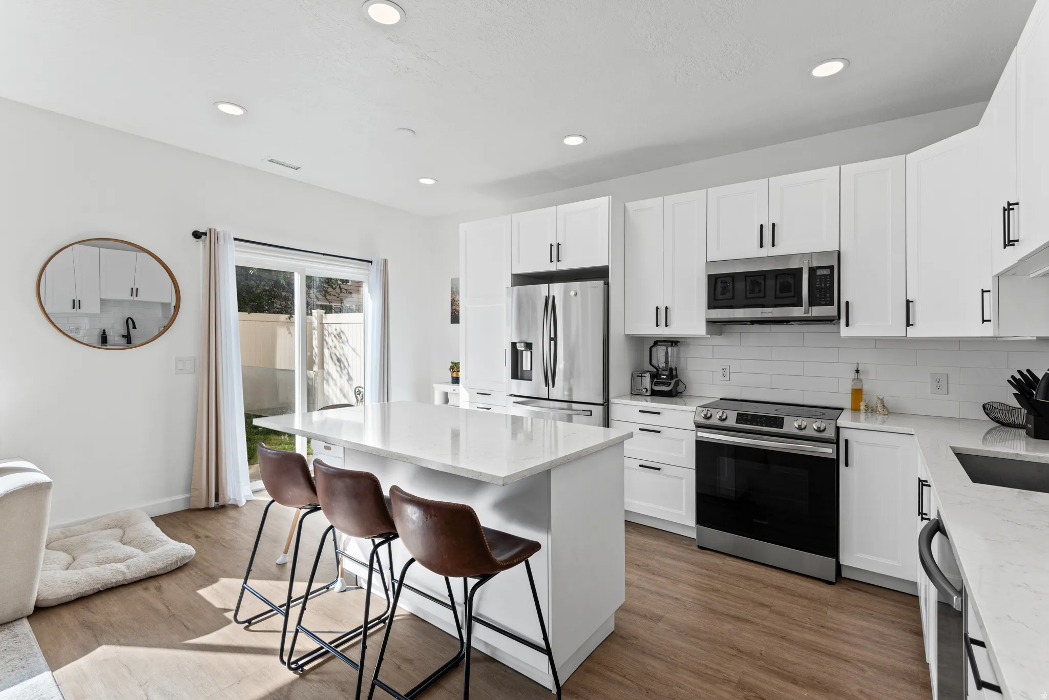 Modern kitchen featuring white shaker cabinetry, stainless steel appliances, a center island with counter seating, and wood-finish flooring