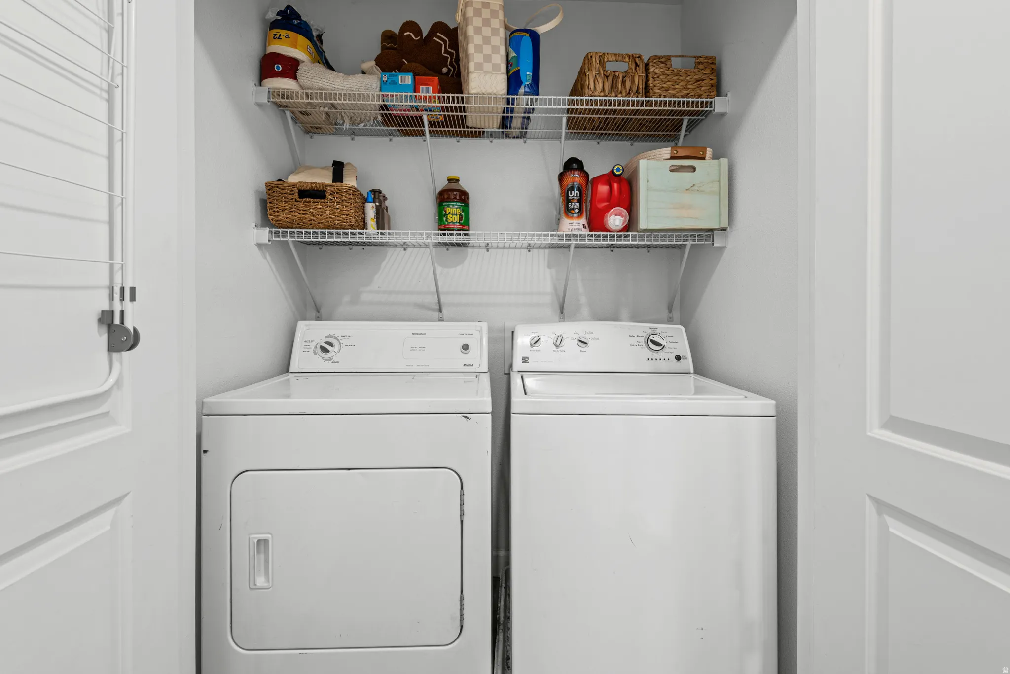 Equipped laundry area featuring a washer and dryer, along with two tiers of wire shelving for storage