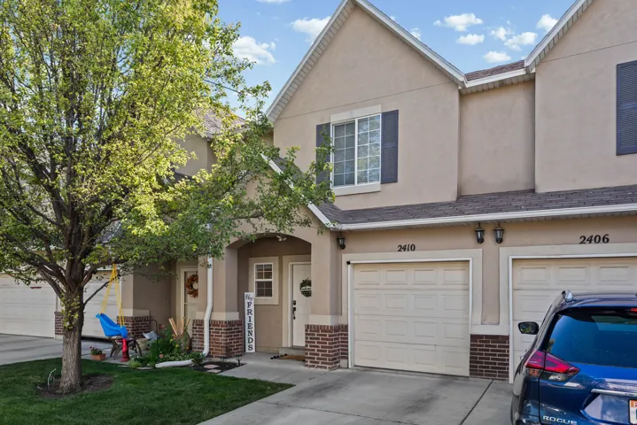 Stucco exterior with brick veneer accents, an attached garage, and a concrete driveway