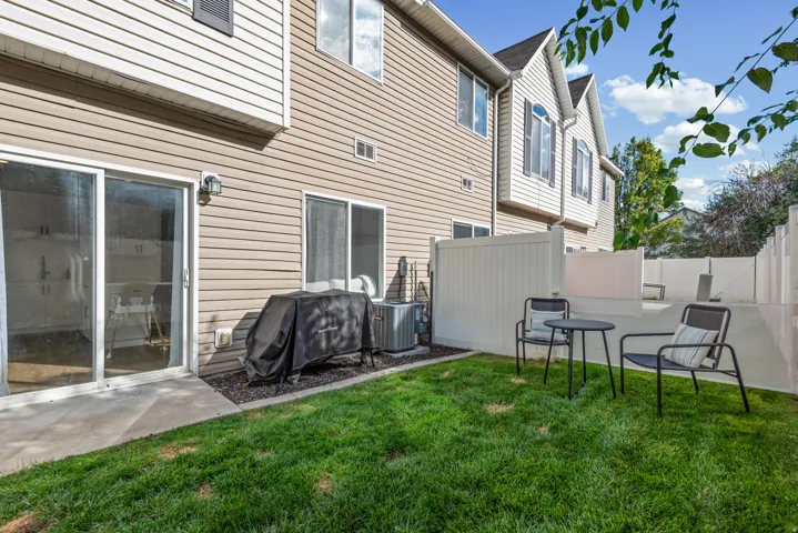 Private fenced backyard featuring a grassy area, concrete patio, and vinyl fencing