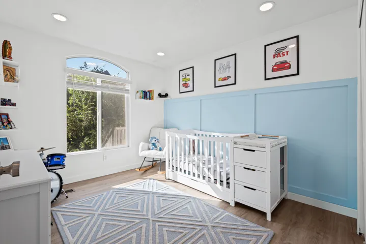 Recessed lighting, wood-finish flooring, white walls, arched window, and blue accent wall paneling