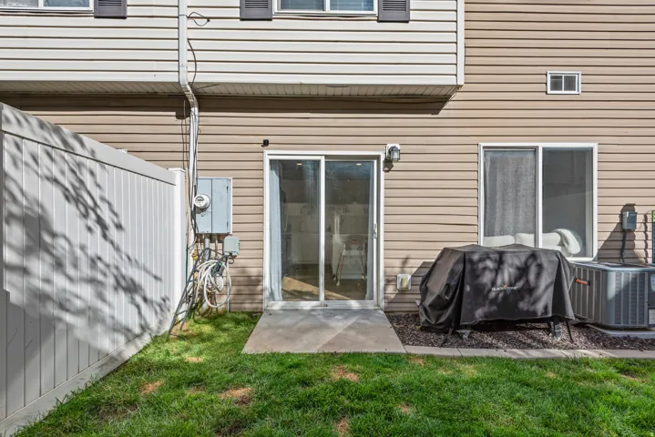 Sliding glass door access, concrete patio, vinyl siding, air conditioning unit, and a privacy fence