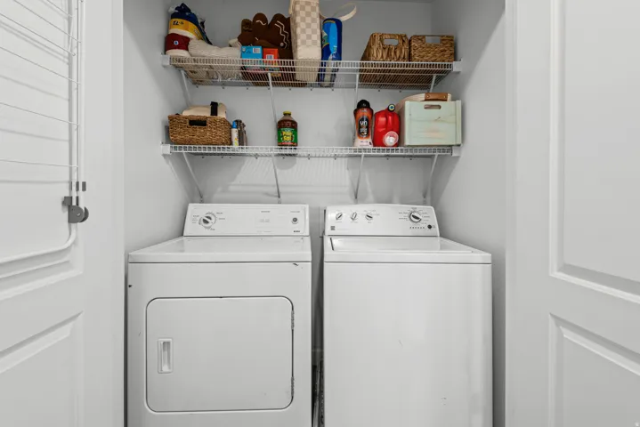 Equipped laundry area featuring a washer and dryer, along with two tiers of wire shelving for storage