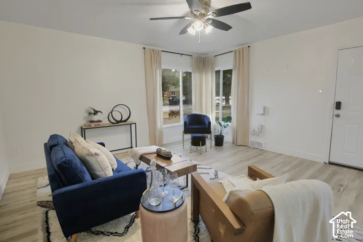 Light-toned wood-finish flooring, white walls, and a ceiling fan with integrated lighting