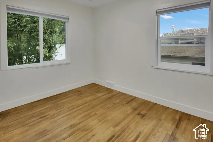 Wood-finish flooring, white painted walls, and two windows with white trim
