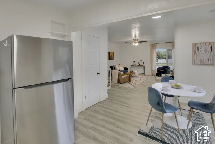 Stainless steel refrigerator, wood-finish flooring, white paneled door, and recessed lighting