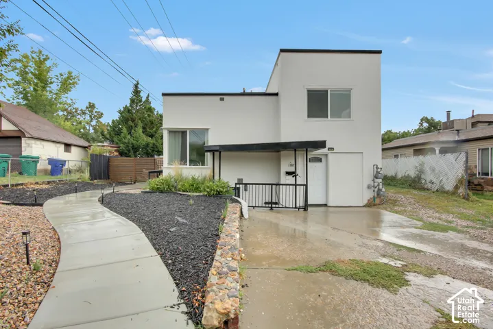 Modern exterior with contrasting trim, a curved concrete pathway, and an entryway featuring a black metal railing
