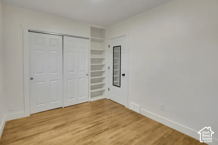 Wood-finish flooring, built-in shelving, white paneled doors, and a transparent door panel with black trim