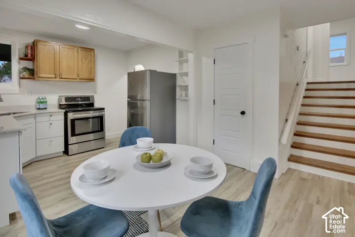 Kitchenette featuring wood-finish flooring, stainless steel appliances, white cabinetry, and light-toned countertops