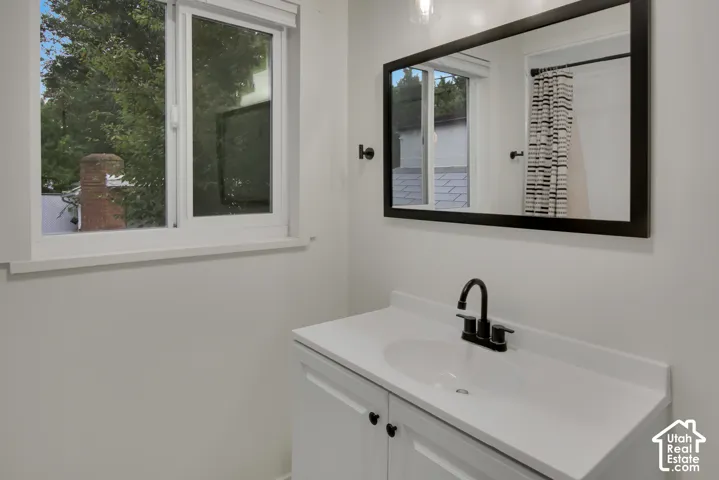 White vanity with an integrated sink and matte black faucet, framed mirror, and a white-framed window