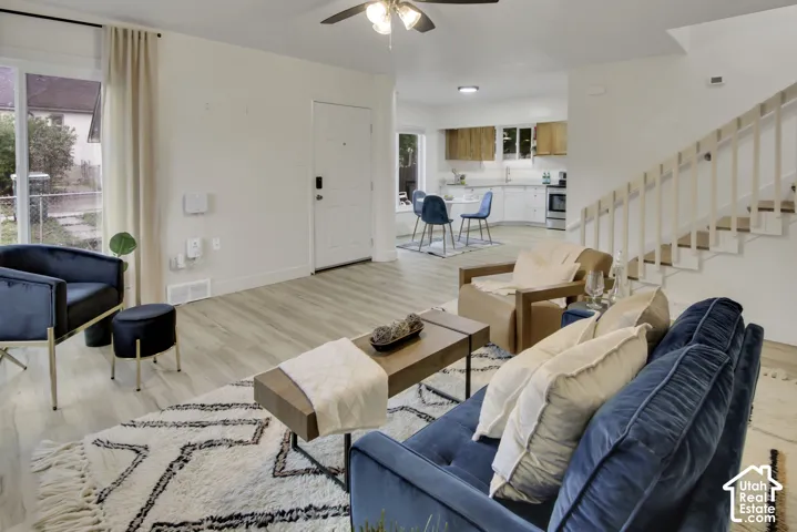 Light wood-finish flooring extends through the living area, complemented by a white painted staircase with wooden railings