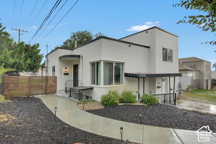 Contemporary stucco exterior with a curved entryway, bay window, and a concrete pathway