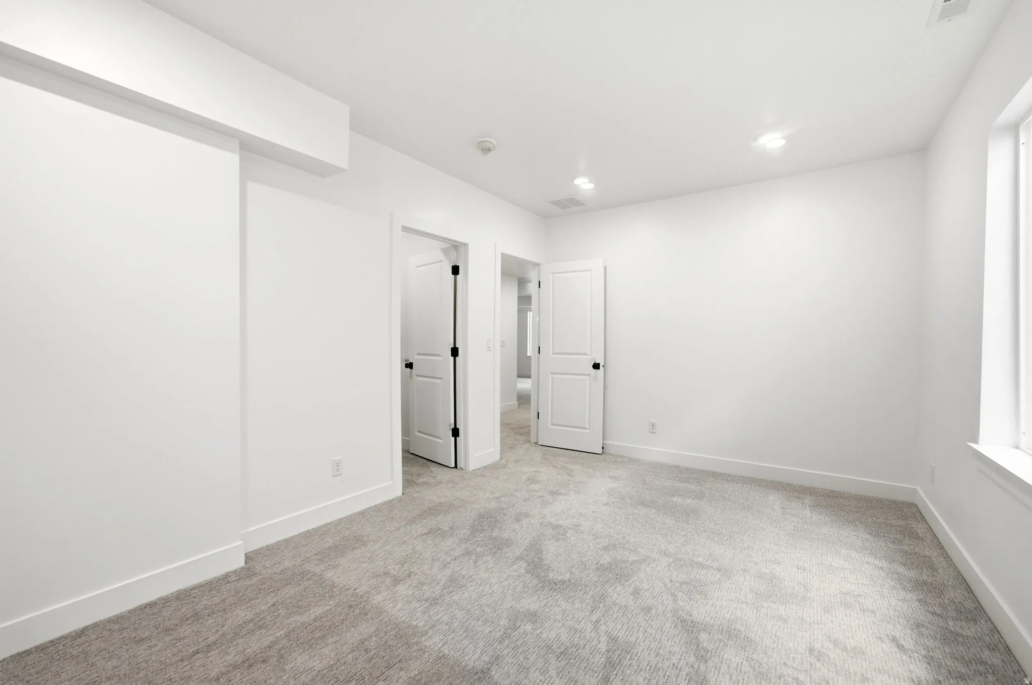 Neutral toned carpeting, white walls, recessed lighting, and white trim