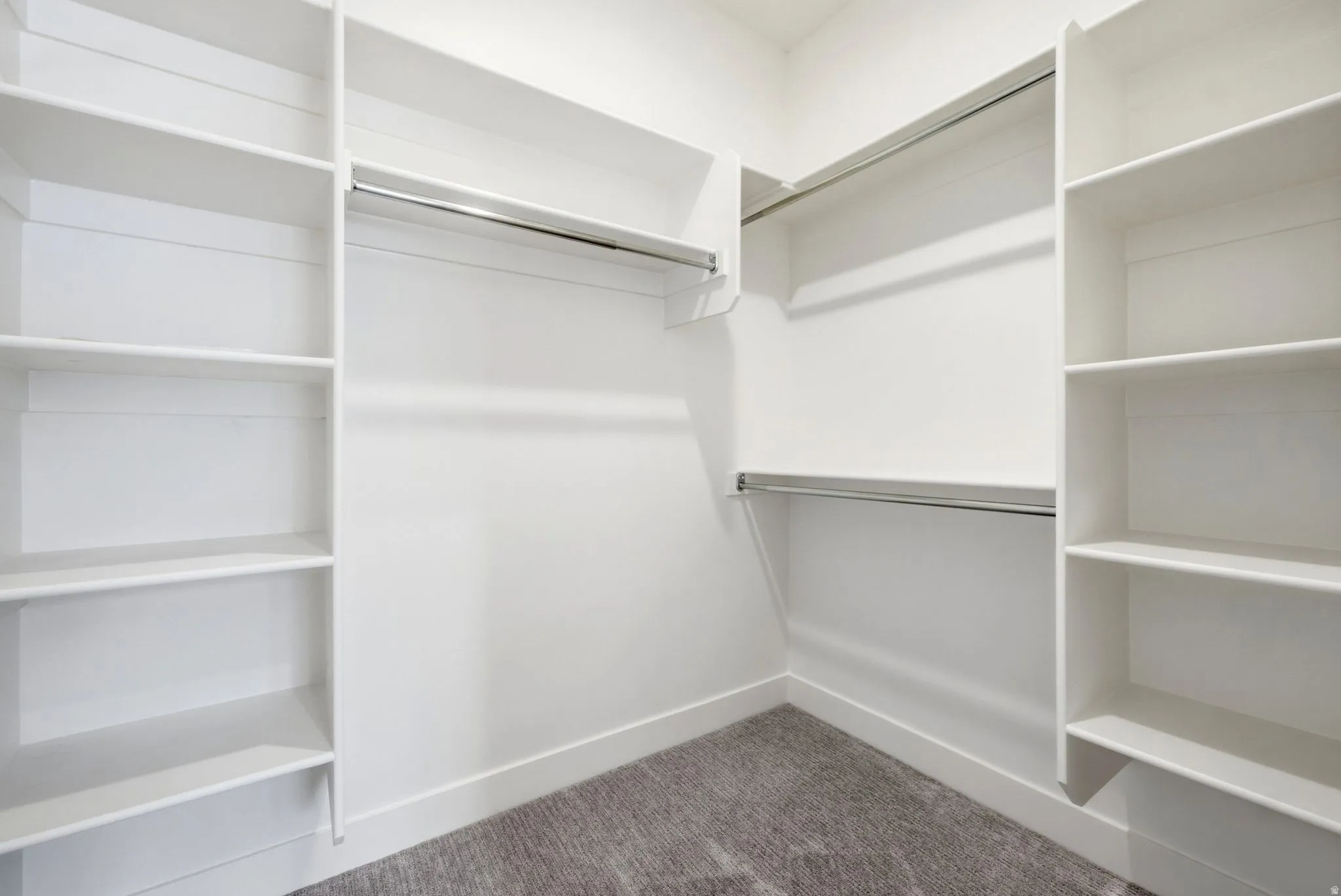 Built-in closet shelving, dual chrome hanging rods, and light-colored carpeting