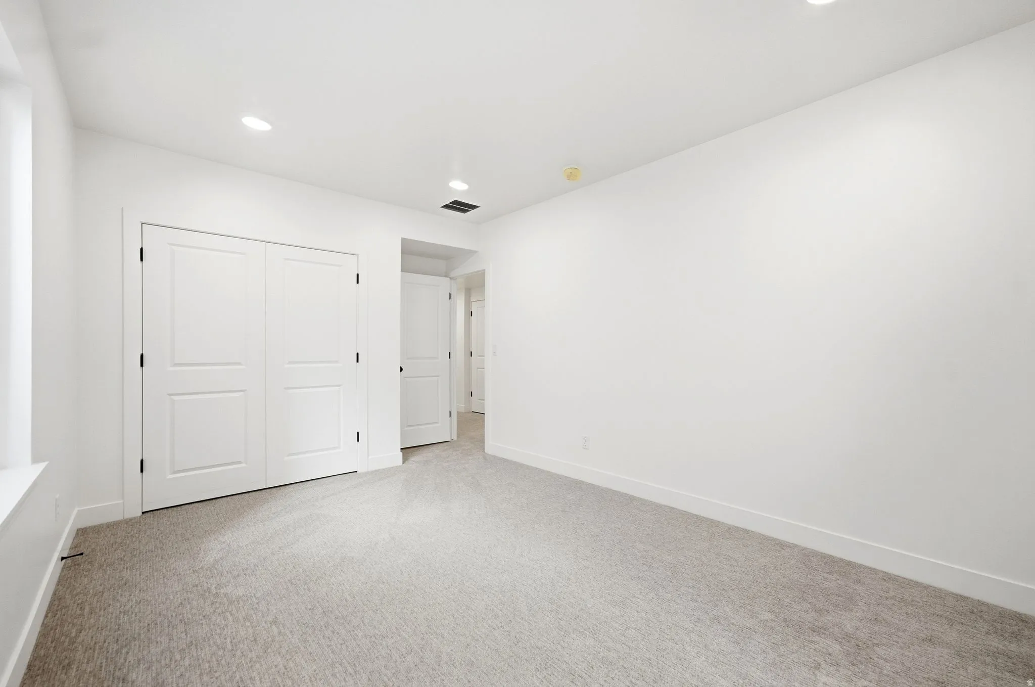 Recessed lighting, neutral wall paint, carpeted flooring, and a window